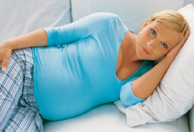 Беременная женщина отдыхает на кровати